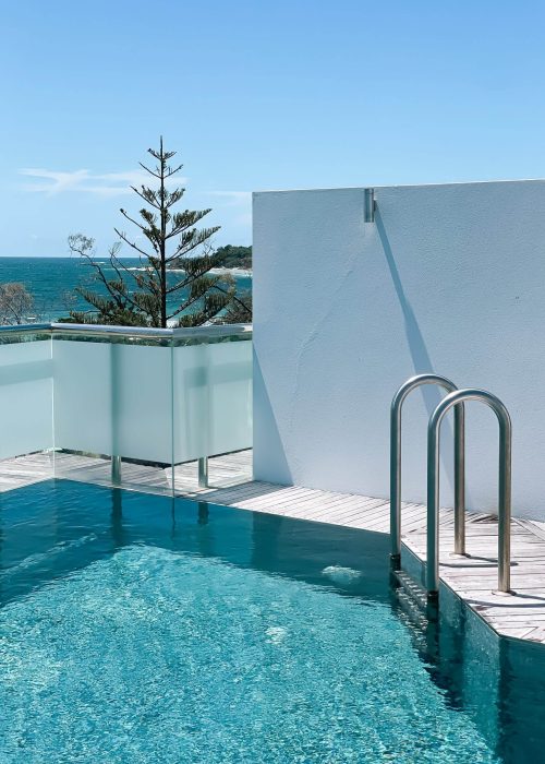 swimming pool with ladder and beach view