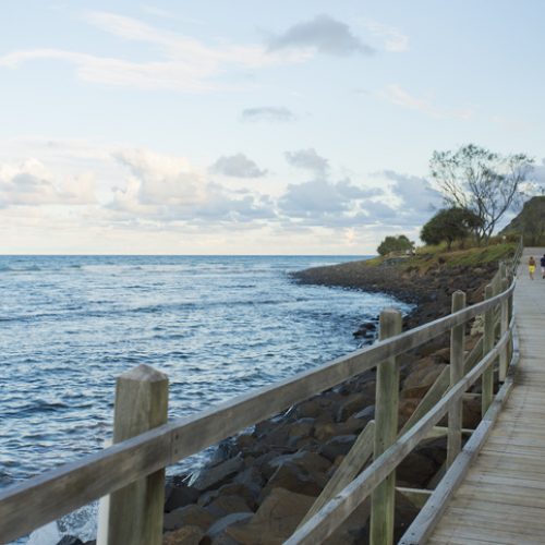 "Lennox Head, NSW, Australia - January 29, 2013: Early evening exercisers walk on the boardwalk by the beach at Lennox Head"